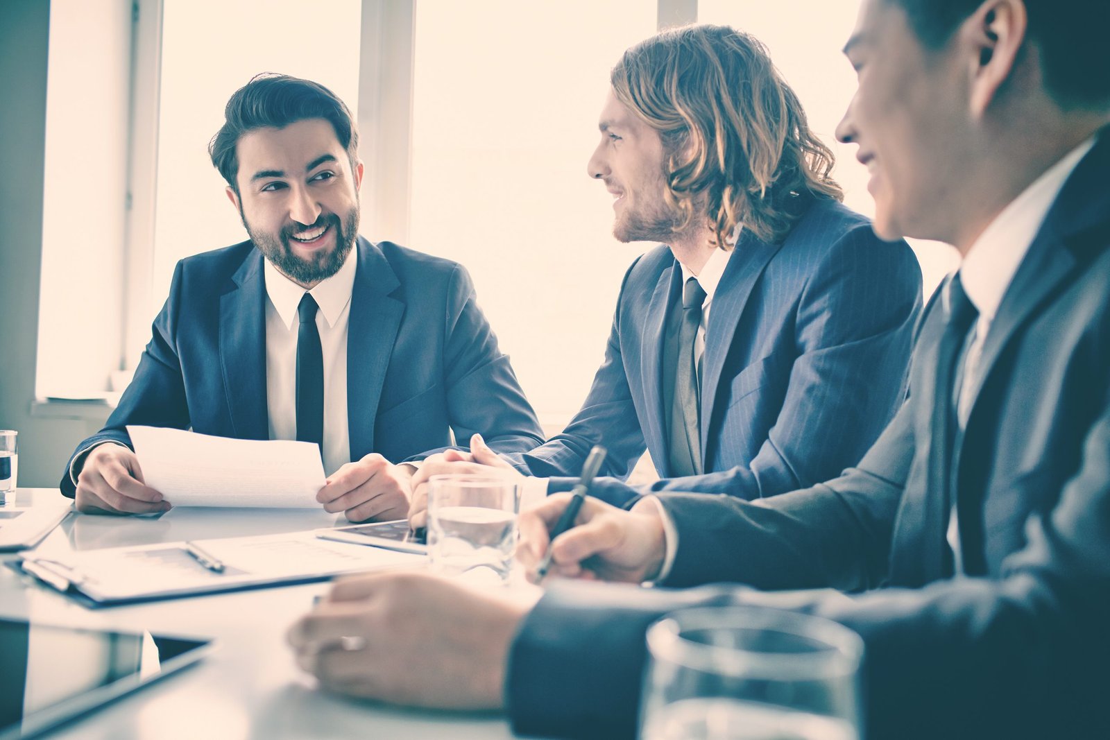 Business Meeting Three business people smiling at a table with work in front of them